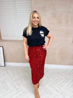 Model wearing a black oversized t-shirt with a graphic skull on the left styled with sequin red midi skirt